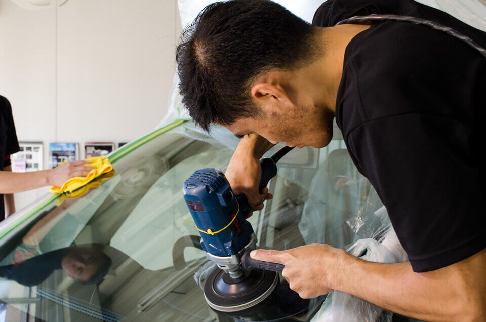 日産セレナにフロントガラス研磨を施工するスタッフ。