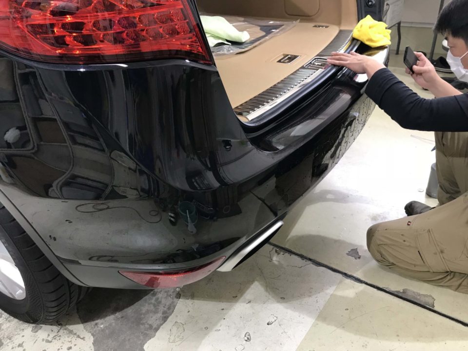 Porsche Cayenneのリアドアバンパーにプロテクションフィルムを貼り付けしているところ